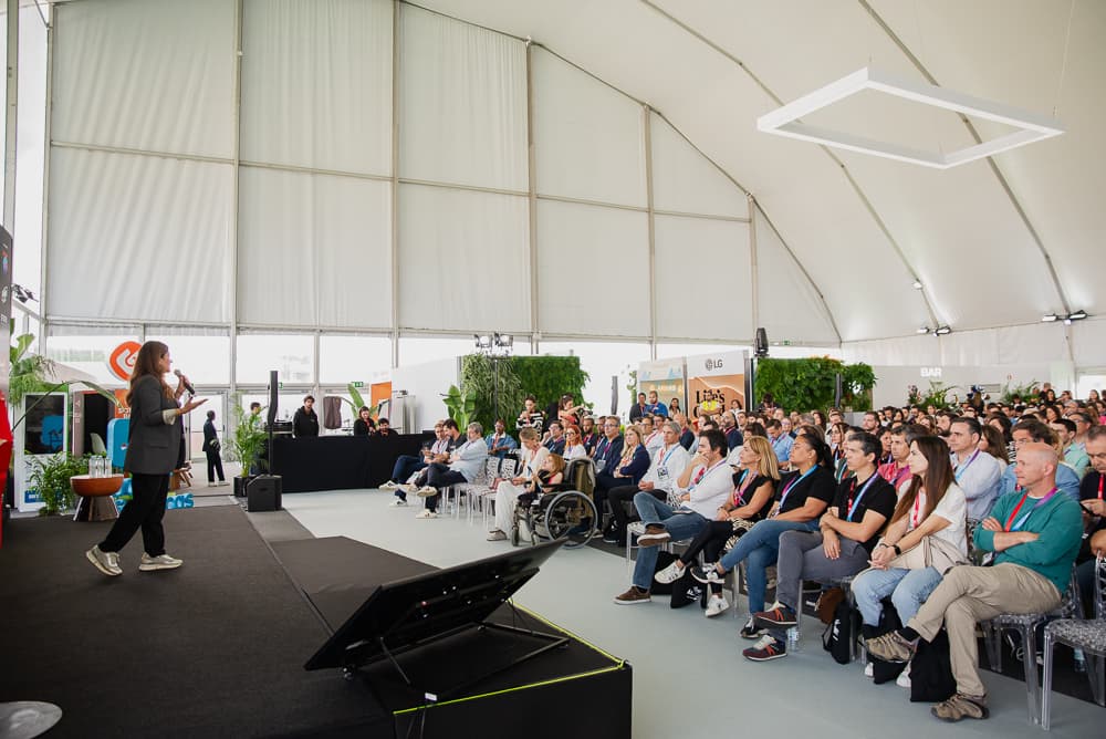 Apresentadora a dirigir-se a uma audiência em evento corporativo numa estrutura de pavilhão